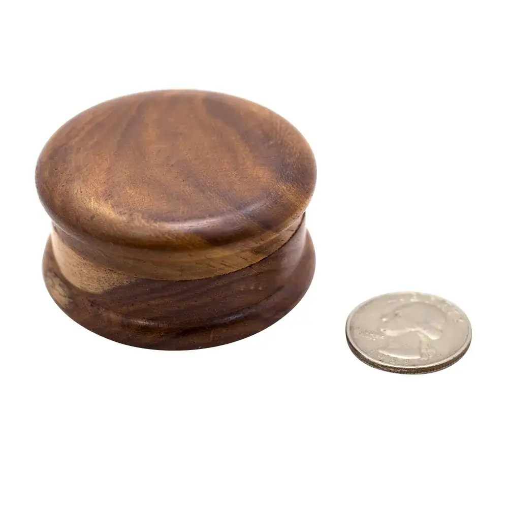 small dark wood grinder with quarter to show scale